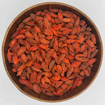 getrocknete goji beeren in runder holzschale von oben rote superfood beeren auf weissem hintergrund