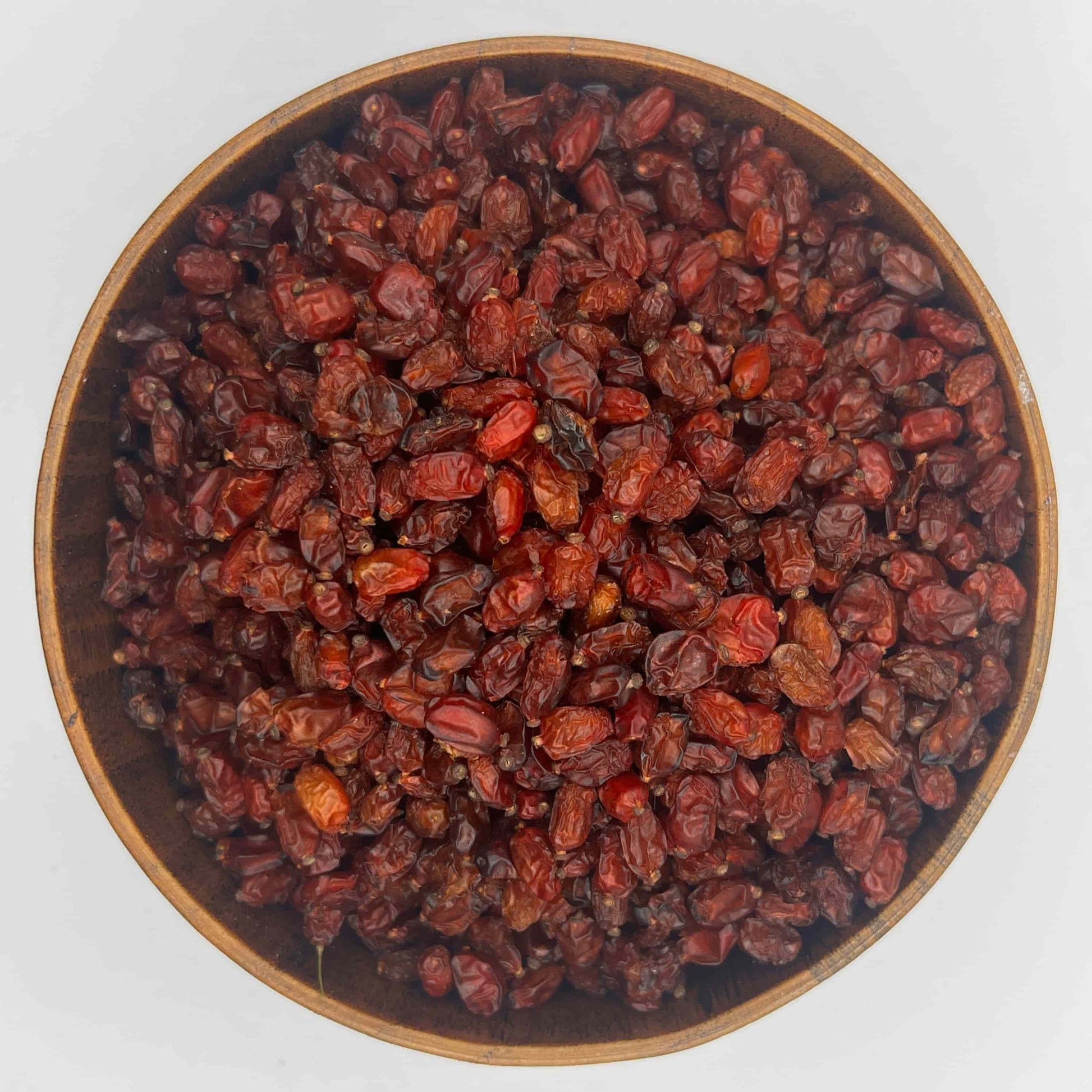 bio getrocknete berberitzen in runder holzschale von oben verkauft am naschmarkt in wien rote saure beeren auf weissem hintergrund