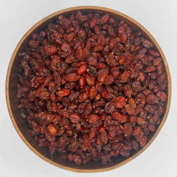 bio getrocknete berberitzen in runder holzschale von oben verkauft am naschmarkt in wien rote saure beeren auf weissem hintergrund