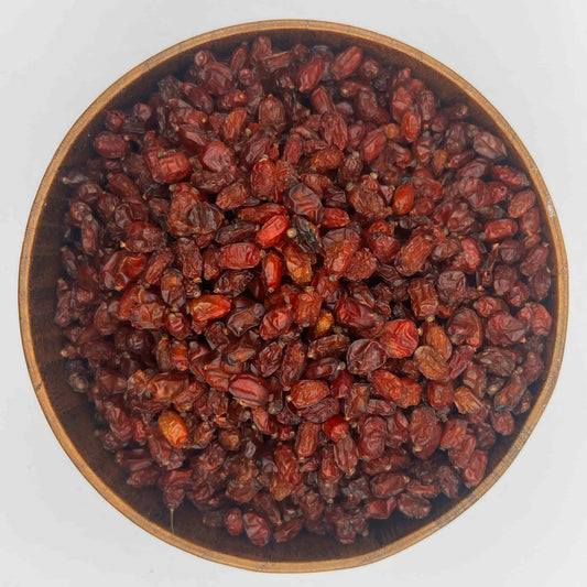 bio getrocknete berberitzen in runder holzschale von oben verkauft am naschmarkt in wien rote saure beeren auf weissem hintergrund