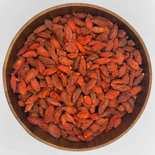 getrocknete goji beeren in runder holzschale von oben rote superfood beeren auf weissem hintergrund