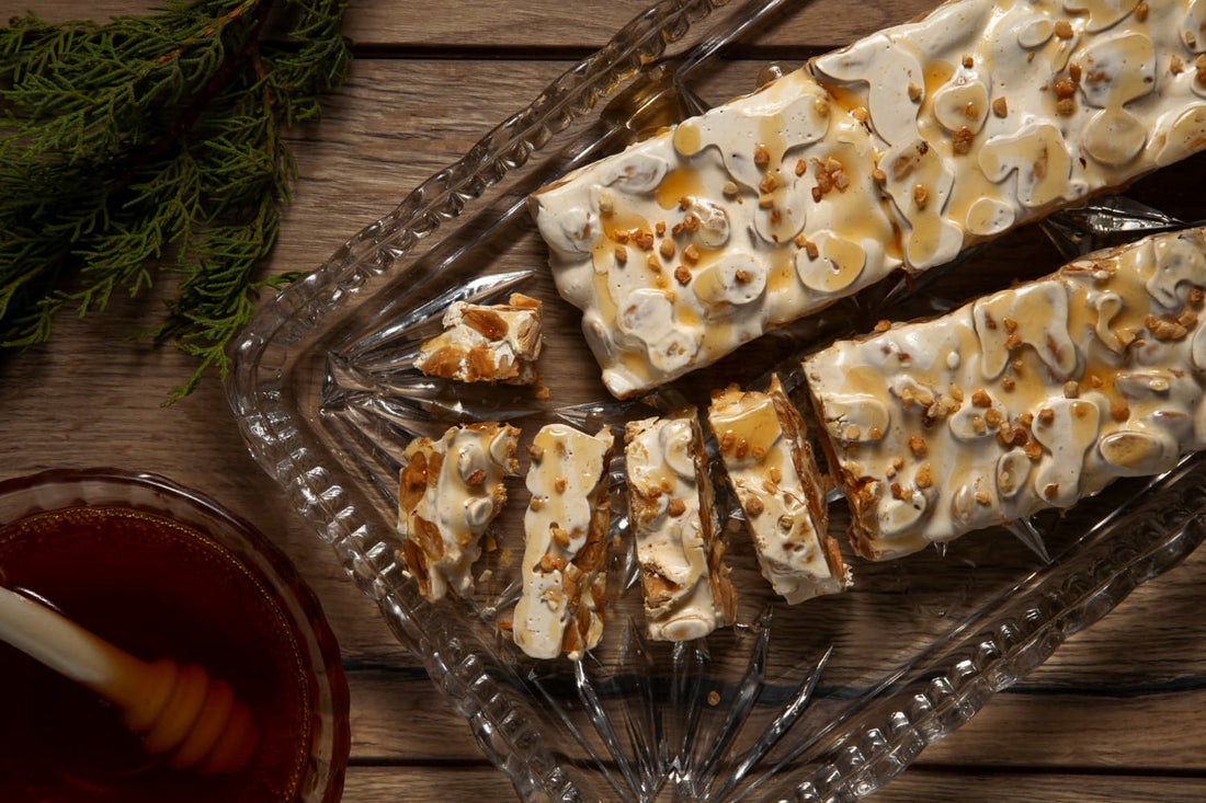 Handgemachter Honig-Nougat mit gerösteten Mandeln auf Glasplatte – süßer Snack aus natürlichen Zutaten, ideal als hochwertiges Geschenk oder Genussmoment